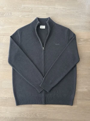Mörkgrå ziptröja från Gant - Mörkgrå ziptröja från Gant med hög krage och diskret logga på bröstet i ett mjuk ull-material. I storlek XL. Nypris runt 1 500kr. Skriv om ni har några frågor eller funderingar😊