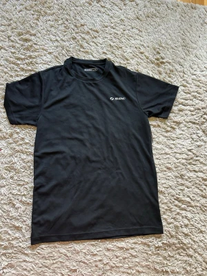 Svart t-shirt från SOC - En stilren svart t-shirt från SOC med rund hals och korta ärmar. Diskret logga på bröstet. Perfekt till träning eller chill. Tillverkad i mjukt material som känns skönt mot huden.