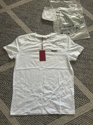 Vit Björn Borg t-shirt  - Helt ny vit t-shirt från Björn Borg med svart logga på bröstet. T-shirten har rund hals och korta ärmar, tillverkad i mjuk bomull för en skön känsla. Perfekt basplagg för alla tillfällen.