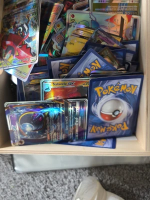 Stor samling Pokémonkort GX & holo - Säljer en stor samling Pokémonkort med flera GX- och holografiska kort. Blandade motiv och färger, vissa med glansig yta och coola effekter. Perfekt för dig som vill utöka din samling eller byta med vänner. Alla kort ligger i en trälåda. 