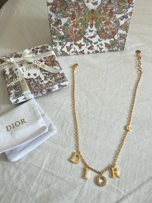 Guldigt halsband med bokstäver och paketering  - Snyggt halsband  i guldfärgad metall med hängande bokstäver. O:et är dekorerat med små gnistrande pärlor och kedjan har en liten stjärndetalj. Perfekt accessoar för dig som vill ha något trendigt och lyxigt.