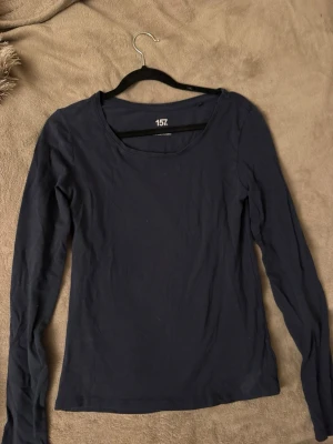 Mörkblå långärmad topp - En enkel och stilren mörkblå långärmad topp med rund halsringning. Perfekt att matcha med jeans eller kjol för en clean look. Tillverkad i mjukt material som känns skönt mot huden.