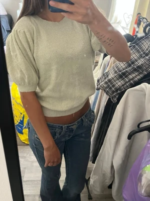 Ljus stickad topp med puffärm - Trendig ljus stickad topp med puffärmar och ribbade muddar. Kortare modell som passar perfekt till jeans eller kjol. Mjuk och bekväm, enkel att styla för en cool vardagslook.