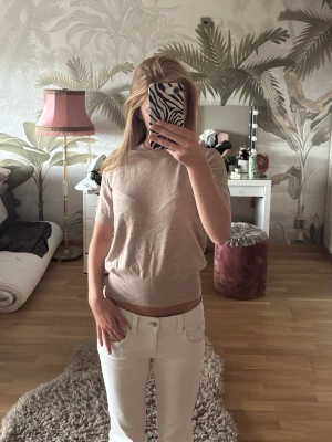 Beige kortärmad topp i bomull från Zara - Snygg beige topp med korta ärmar och rund hals. Tillverkad i mjuk bomull med en enkel och clean look. Passformen är lösare längre upp mot överkroppen och lite thigthare runt midjan. Toppen är perfekt att matcha med jeans eller kjol för en avslappnad stil. Slutsåld från Zara! 
