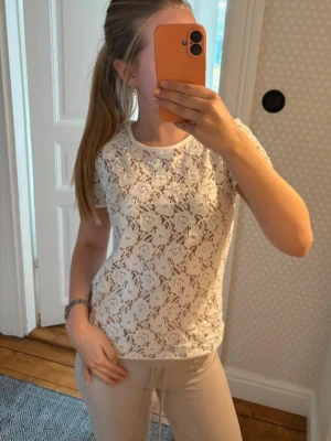 Vit spetsblus från Vero Moda - Säljer en superfin vit blus från Vero Moda i genombruten spets med blommigt mönster. Kortärmad modell med rund halsringning och normal passform. Perfekt att styla med jeans eller kjol för en trendig look. Storlek M men eftersom det ej är stretchigt passar det S och mindre strl 