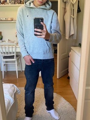 Ralph Lauren hoodie. - Säljer en stilren grå hoodie från Polo Ralph Lauren med liten mörkblå logga på bröstet. Hoodien har huva, magficka och ribbade muddar vid ärmslut och nederkant. Perfekt för en avslappnad och snygg look.