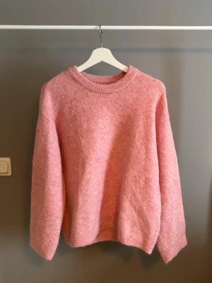 Ljusrosa stickad tröja - Mysig  stickad tröja med rund halsringning. Tröjan har en avslappnad passform och är tillverkad i ett fluffigt, mjukt material som känns skönt mot huden.  Använd fåtal gånger så mycket fint skick i storlek XS