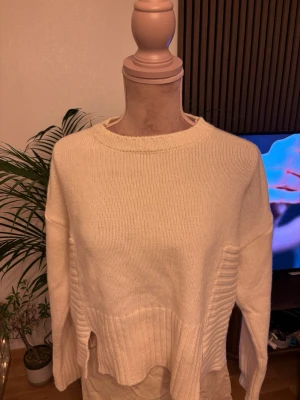 Krämvit stickad tröja med slitsar - Säljer en fantastiskt mjuk och lyxig stickad kvalitetströja från det italienska designmärket PINKO. Modellen heter ”Armadillo Maglia Warm” och är tillverkad i Italien av en förstklassig blandning bestående av 90% ull och 10% kashmir – otroligt varm, mjuk och behaglig mot huden.Tröjan är i en tidlös gräddvit/off-white nyans med en modern, avslappnad silhuett. Nypris 3 700kr
