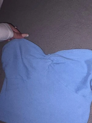 Ljusblå ribbad bandeau topp - Supersöt ljusblå bandeau topp med ribbad struktur och en snygg twistdetalj framtill. Toppen är axelbandslös och har en croppad passform som passar perfekt till både jeans och kjol. Perfekt för varma dagar eller sommarens alla äventyr.