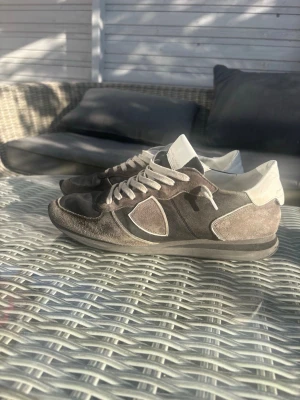 Bruna mockasneakers med vita detaljer - Snygga sneakers i brun mocka med vita detaljer och vita skosnören. Skorna har en klassisk låg siluett och en bekväm sula. Perfekta för dig som gillar en stilren och avslappnad look.