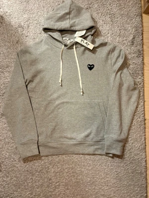 Commes des garçons hoodie  - Säljer nu denna gråa hoodien från Commes des garçons. Tröjan är helt ny och i perfekt skick. Storleken är M och skulle säga att den passar cirka ~ 180-185cm. Skriv vid frågor!