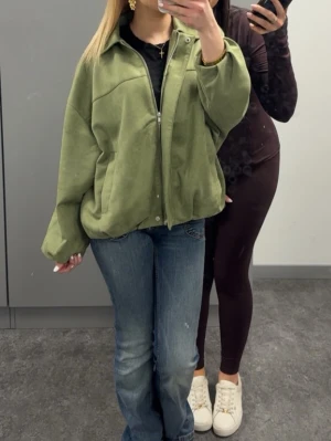 Grön oversized teddyjacka från Nelly - Säljer en grön oversized jacka från Nelly med dragkedja framtill och krage. Perfekt att slänga över en hoodie eller t-shirt för en chill stil. Använd 1 gång ! 