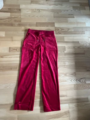 Röda Juicy Couture byxor - Röda Juicy couture byxor i storlek xs. Benen är uppfållade så att de passar en person runt 160cm