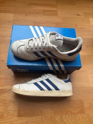 Adidas gazelle - Snygga adidas gazelle sneakers perfekta till vardagen! Som man ser på bilderna har dem använts en del men dem har fortfarande mycket kvar att ge! Inga riktiga defekter utom lite lätt missfärgning och skrapor. Boxen medföljer ifall man vill det! Storleken är 41 och 1/3 men sitter som 41. Hör gärna av dig med frågor eller prisförslag!