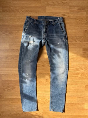 Blå slitna donups jeans - Säljer nu dessa väldigt snygga Dondup jeans med snygga slitningar! Storlek 33 men sitter mer som 31/32. Fixar gärna mått så bara skriv isåfall👍modellen är 185,74 kg.