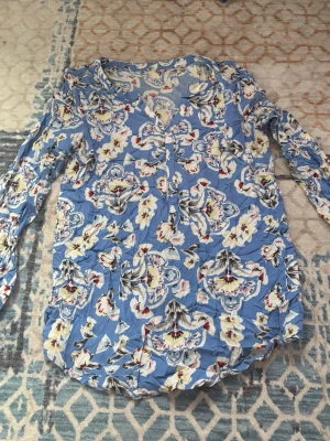 Blommig blå blus med knappar - Snygg blus i ljusblått med blommigt mönster.