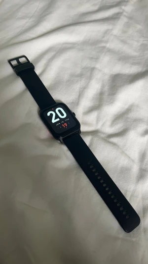 Svart smartklocka med silikonarmband - Snygg svart smartklocka med fyrkantig display och svart silikonarmband. Klockan har en modern design med tydlig digital urtavla och en knapp på sidan för enkel navigering. Perfekt för dig som vill ha koll på tiden och notiser direkt på handleden. (Kommer med laddare)