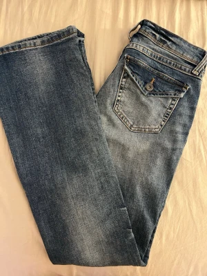 Blå flared jeans från H&M  - Snygga blå jeans med utsvängda ben och klassisk femficksdesign. Jeansen har en extra ficka med knapp på baksidan och slitningar för en cool look. Med låg midja. 