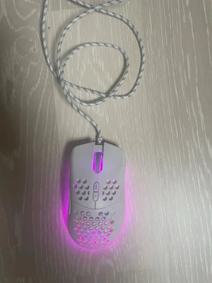 Vit gamingmus med RGB-belysning kopplingsbar ps5/xbox - Säljer en vit gamingmus med hålat skal och RGB-belysning som lyser i rosa och andra fina färger. Musen har sladd med mönstrad kabel och extra knappar på ovansidan. Perfekt för dig som vill ha en lätt och snygg mus till datorn.