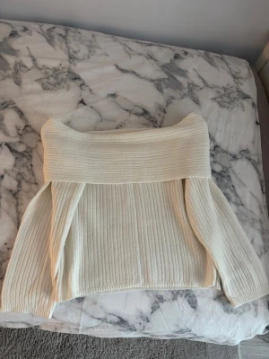 Off shoulder stickad tröja H&M - Säljer en krämvit off shoulder stickad tröja från H&M. Tröjan har bred ribbstickning, lång ärm och en bred krage som kan bäras nedanför axlarna. Perfekt för dig som vill ha en trendig och mysig look.Den är inte använd helt ny utan prislapp