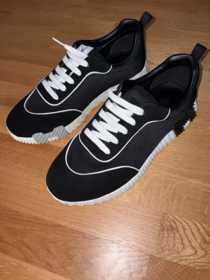 H skor - Snygga svarta sneakers med vit, räfflad sula och vita detaljer. Skorna har vita snören och en modern design med kontrasterande linjer. Materialet ser ut att vara en mix av textil och syntet. Perfekta för dig som gillar stilrena och trendiga skor. Utan box!!