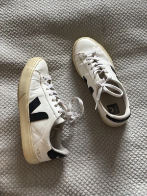 Vita Veja sneakers med svart detalj - Snygga vita sneakers från Veja med svart V-logga på sidan och beige sula. Köpta nya på zalando för 1800 men de är bra använda💕Kom med förslag på pris om ni är intresserade💕