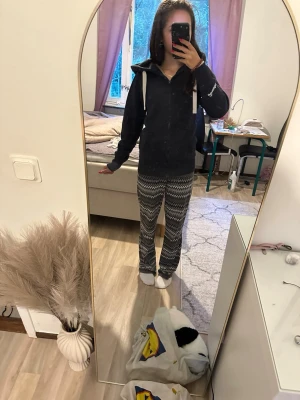 Mönstrade pyjamasbyxor i svartvitt - Säljer ett par mysiga pyjamasbyxor med svartvitt zigzag-mönster. Byxorna har rak passform och resår i midjan för extra komfort. Perfekta för chill hemma eller sovmorgon. Materialet ser ut att vara mjukt och stretchigt, troligen bomull eller bomullsblandning.