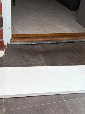 Vit tröskel i trä - Säljer en vitmålad tröskel i trä, perfekt för att täcka övergången mellan två golvytor. Enkel och stilren design som passar de flesta hem. Tröskeln är rektangulär och har släta kanter.