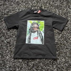 Svart Supreme t-shirt - Tja, säljer nu denna feta Supreme T-shirt 🔥 Storlek M och i fint skick. Fet graphic framtill med den klassiska röda Supreme-loggan. Riktigt snygg streetwear-tee som sticker ut men ändå är lätt att matcha.  Tveka inte på att höra av dig vid fler frågor eller funderingar 😁