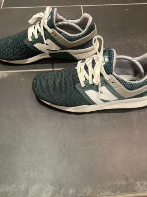 Mörkgröna New Balance sneakers - Snygga mörkgröna sneakers från New Balance med vit sula och vita detaljer. Ovandelen är i mesh-tyg för bra andningsförmåga och skorna har klassiska vita snören samt den ikoniska N-loggan på sidan. Perfekta för en sportig och avslappnad stil. Pris kan diskuteras.
