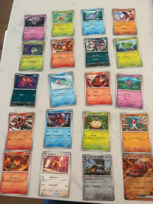 Pokémonkort samling japanska - Samling med över 20 Pokémonkort på japanska. Korten har olika färger och motiv, inklusive eld, vatten, gräs, stål och psykisk typ. Ett av korten är ett större GX-kort med eldtema. Perfekt för dig som gillar Pokémon, anime och samlarkort. Alla kort är i klassiskt rektangulärt format och tryckta på papper.