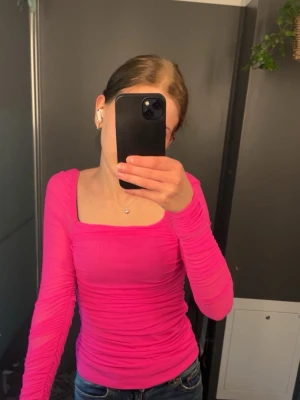 Rosa långärmad topp med rynk - Säljer en snygg långärmad topp i stark rosa färg. Toppen har fyrkantig ringning både fram och bak samt rynkade detaljer över hela plagget. Materialet är stretchigt och sitter tight mot kroppen. Perfekt för dig som vill sticka ut med färg! Från SHEIN. Oanvänd. Prislapp finns kvar. Är strl 36 men passar mig som är en 32. 