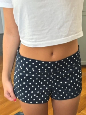 Mörkblå prickiga shorts - Snygga mörkblå shorts med vita prickar och två framfickor. Shortsen är från Zara helt nya med prislappen kvar, den kommer inte till användning. Den är i storlek 36.