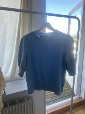 Ljusblå stickad tröja Vero Moda - Säljer en ljusblå stickad tröja från Vero Moda med rund halsringning och puffiga ärmar. Tröjan har ribbade muddar vid ärmslut och nederkant, vilket ger en snygg och bekväm passform. Perfekt för dig som gillar en enkel men trendig look.