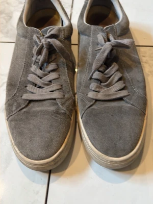 Grå mockasneakers från Vagabond - Snygga grå sneakers i mocka från Vagabond med klassisk låg profil och matchande grå skosnören. Skorna har en vit sula och enkel design som passar till det mesta. Perfekta för dig som gillar stilrena och bekväma sneakers.