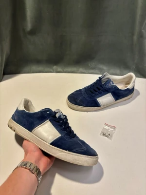 Valentino Flycrews - Säljer ett par riktigt fina Valentino Flycrews i marinblå mocka, svåra att få tag på då det ej tillverkas längre. Okej skick, finns tecken på användning. Några nitar saknas (7 extra nitar tillkommer vid köp). Nypris ligger runt 6500kr, säljs för 1800kr ! 