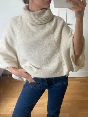 Beige stickad poncho med polokrage - Säljer en oversized stickad poncho med  polokrage och vida ärmar🩷