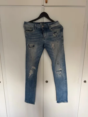 Ljusblåa jeans från Jack & Jones med slitningar - Säljer dessa riktigt feta ljusblå slim fit jeans med slitningar från Jack & Jones, pris ej hugget i sten, hör av dig vid funderingar!