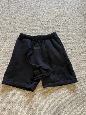 Essentials shorts - Ett par svarta essentials shorts med svart text nere vid vänstra benet. De är i storlek M och i nytt skick. Pris kan diskuteras och skriv om du har några frågor. 