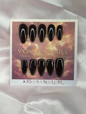 Molten (XS);Medium Almond - Handgjorda press-on naglar i svart med en cateye röd crackle-effekt. Cateye effekten syns även under naglarna. Medium långa, och mandelformade för en edgy look. Perfekta för dig som vill sticka ut med unika naglar. Kommer i storlek XS: 14 mm, 11 mm, 11,5 mm, 10 mm, 8 mm