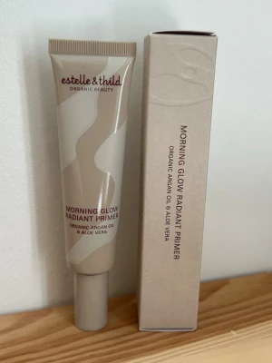 Morning Glow Radiant Primer - Primer från Estelle & Thild i beige tub med vågigt mönster. Innehåller ekologisk arganolja och aloe vera för en naturlig glow. Tuben rymmer 30 ml och har en smidig applikator. Kommer i matchande kartong med minimalistisk design.