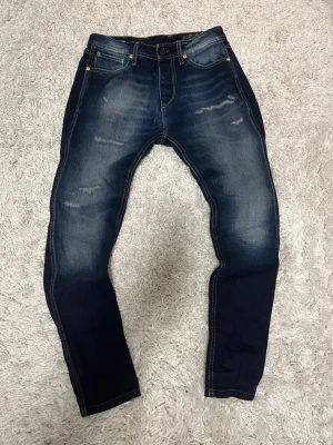 Mörkblå jack and jones archivr vintage jeans. - Säljer dessa snygga vintage jeans från jack and jones. Storlek 30/32. Feta slitningar framtill och skön tvätt både fram och bak. Lite smala där nere