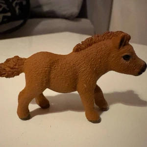 Schleich häst - Säljer en brun hästfigur i plast med detaljerad man och svans. Figuren har svarta ögon och gråa hovar. Perfekt som leksak eller dekoration för dig som gillar djur och samlarfigurer.