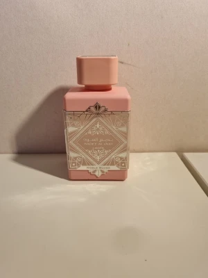 Lattafa BAKHOOR AL OUD parfym till salu! - Säljer en elegant parfym. Parfymen luktar kokunöt. Flaskan är Matt rosa med silverfärgad dekor och orientaliskt mönster. Flaskan har fyrkantig form och matchande lock. Texten på etiketten är både på arabiska och engelska, och doften heter BAKHOOR AL OUD NOBLE BLUSH.