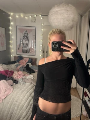 Svart offshoulder topp med lång ärm - Snygg svart offshoulder topp med lång ärm och tight passform. Toppen är croppad och har en stilren, enkel design som passar perfekt till höga jeans eller kjol. Materialet känns mjukt och stretchigt, vilket gör den bekväm att bära.