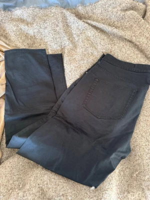 Svarta jeans från Gant - Snygga svarta jeans från Gant med klassisk femficksdesign och raka ben. Jeansen har diskreta detaljer och en bekväm passform. Perfekta för dig som gillar stilrena och tidlösa plagg. Materialet känns mjukt och följsamt.