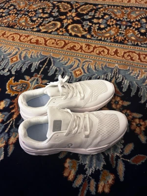 On cloud Vita On sneakers med meshdetaljer - On cloud sneakers storlek 45. Säljer ett par helvita sneakers från On med snygga meshdetaljer för extra ventilation. Skorna har klassisk låg profil, vita snören och diskret logga på sidan. Ovandelen är i textil och syntet, vilket ger en sportig och fräsch look.