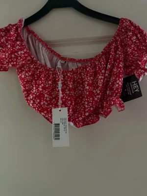 Röd blommig croppad topp - Söt röd croppad topp med små vita blommor och korta puffärmar. Den är väldigt kort 