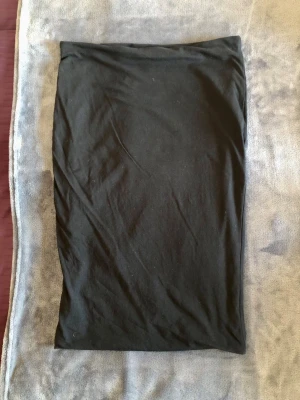 Svart midikjol H&M Basic – Retro/Y2K Strl M - Klassisk och mångsidig svart midikjol från H&M Basic i bekväm och stretchy trikå (95% bomull, 5% elastan). Enkel tubmodell med resår i midjan som passar perfekt för en minimalistisk Retro/Y2K-look. Går ungefär till knät. Mått: • Midja platt: 39 cm (omkrets ca 78 cm, stretchy) • Längd: 64 cm Storlek M. I fint begagnat skick!