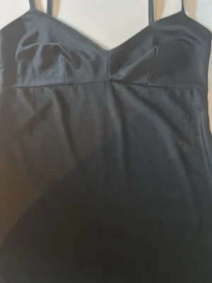 Svart kort Dolce & Gabbanaklänning med tunna band - Snygg svart kort Dolce & Gabbana klänning med tunna axelband och v-ringad urringning. Klänningen har en enkel och stilren design som passar perfekt till många olika tillfällen. Materialet känns mjukt och följsamt mot kroppen. Längd 83 cm bredd 35cm under bysten